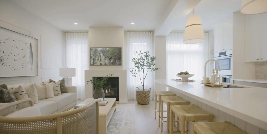 The same living room after renovation, opened to a new kitchen island with a lighter palette and a refaced fireplace